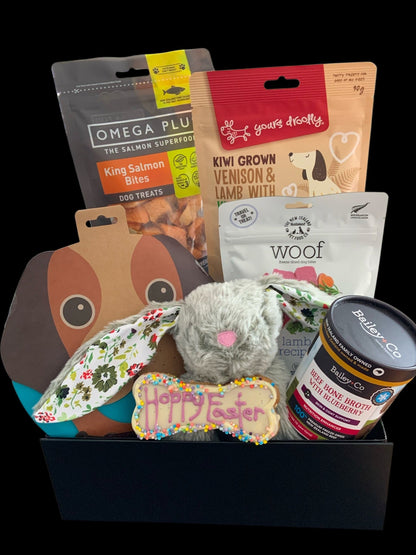 Dog gift basket with various treats and toys on a black background